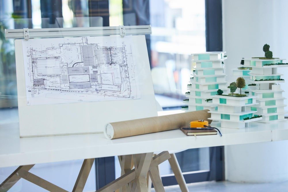 Ritning och litet modellhus på ett arkitektbord